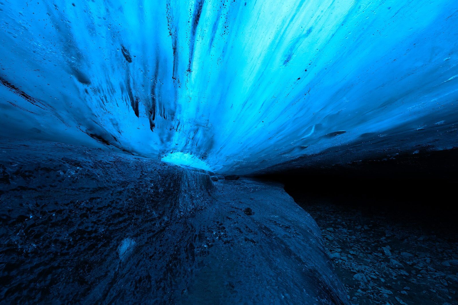 Daylight glowing through the blue ice ceiling of a natural glacier cave under Vatnajökull, Iceland