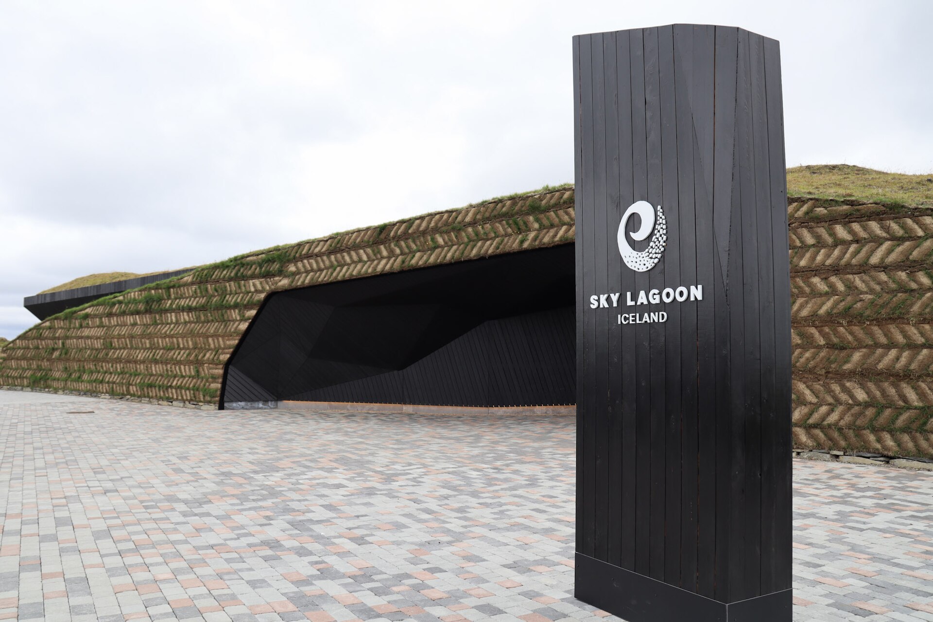 The turf-walled entrance building at Sky Lagoon in Kópavogur, with the black timber entrance sign in the foreground